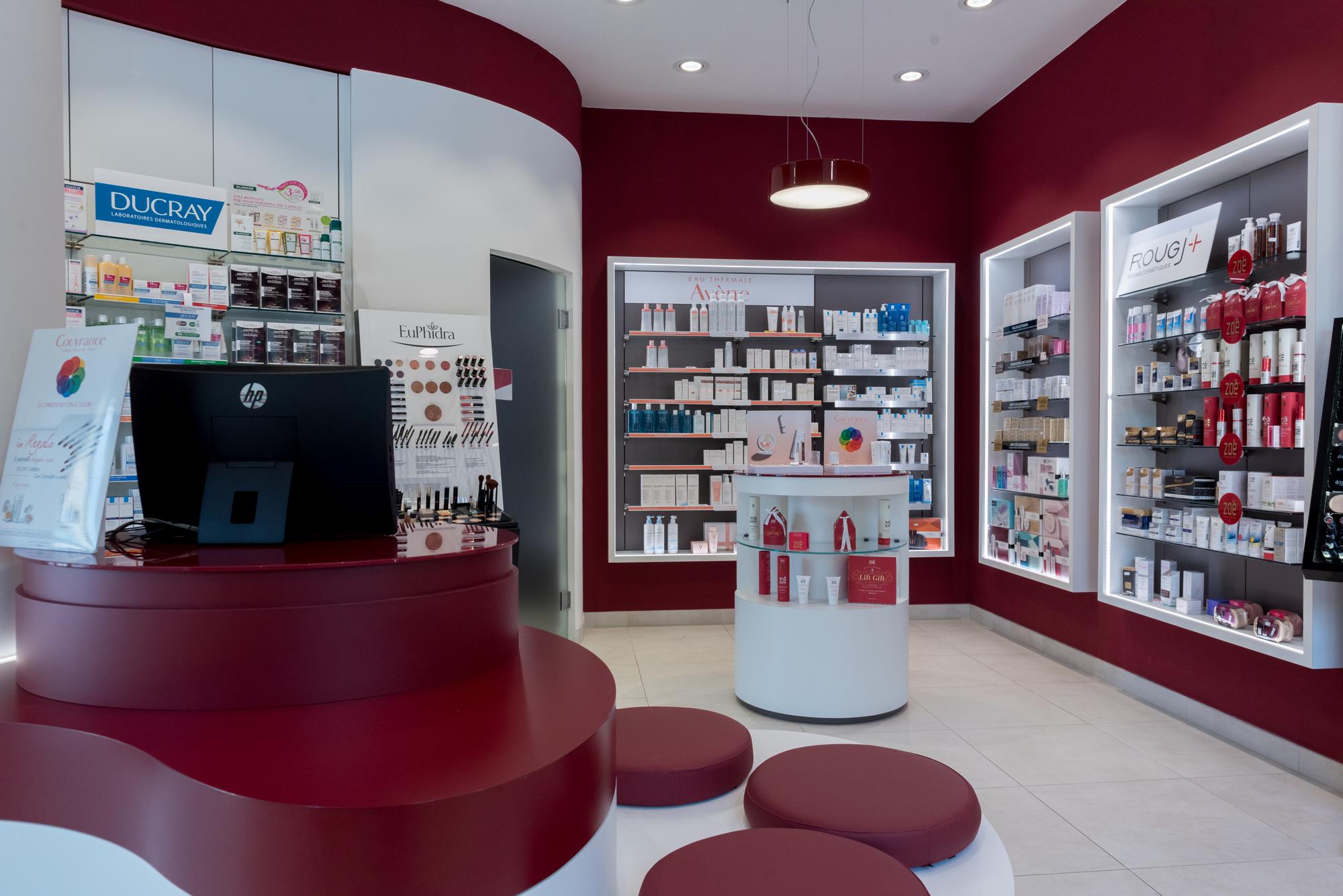 Area dermocosmesi con cabina estetica e sgabelli rossi della Farmacia del Corallo a Livorno